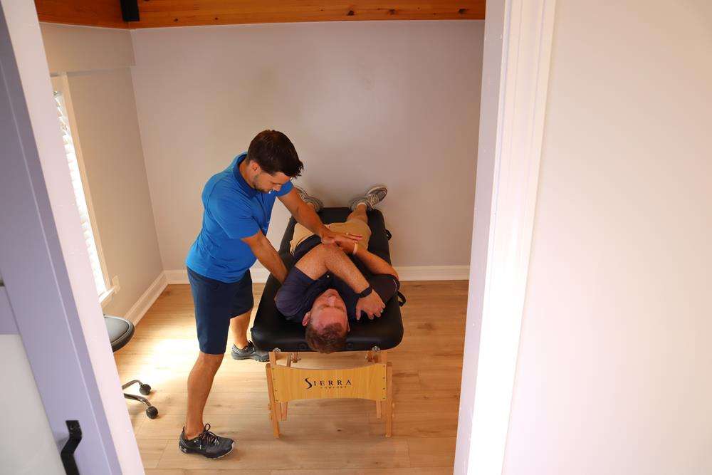 A Doctor of Physical Therapy guiding a lower back and hamstring stretch on the treatment table