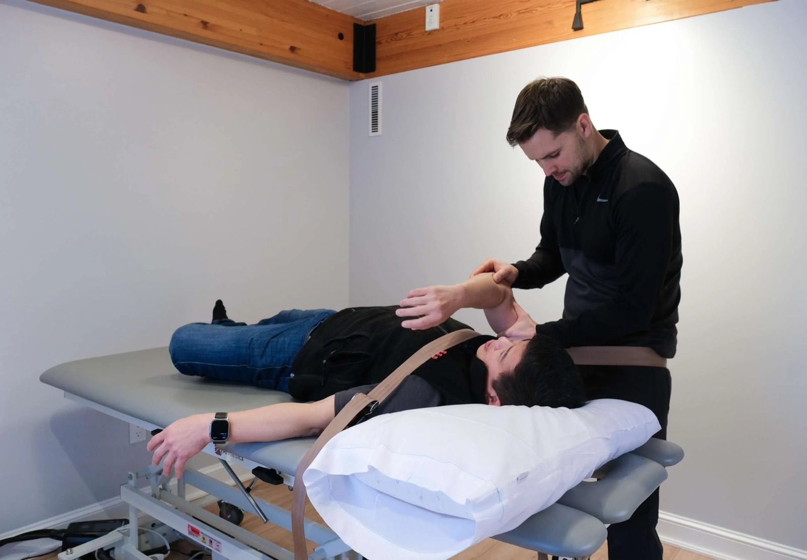 A Doctor of Physical Therapy performing hands-on manual therapy on a patient's shoulder at the treatment table